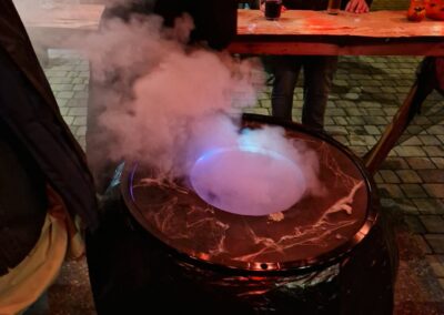 Nebelschwaden steigen aus dem violett beleuchteten Hexenkessel mit Spinnweben an der Hexenhütte